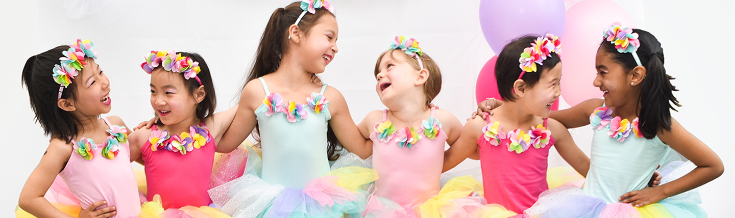 6 Girls laughing in a row wearing Tutu's